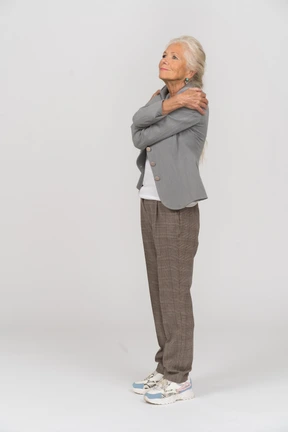 Side view of an old lady in suit hugging herself