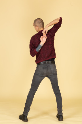 Vista traseira de um jovem de blusa vermelha esticando os braços
