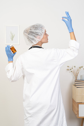 Back view of a young female doctor checking pills