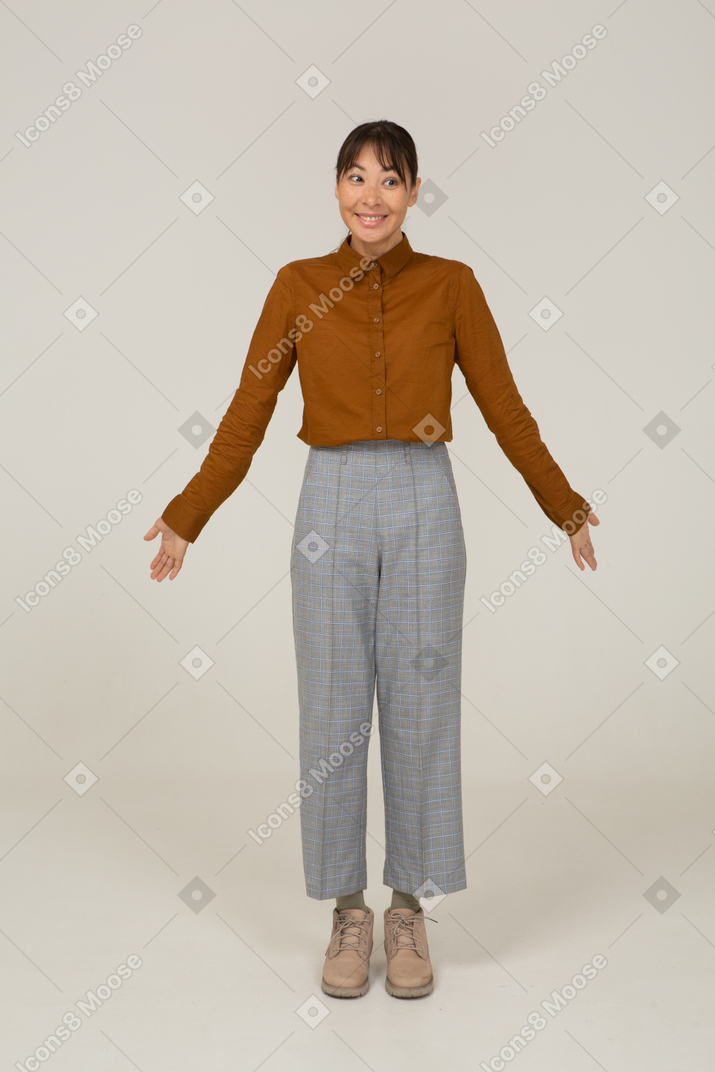 一个微笑的年轻亚洲女性的前视图，穿着马裤和衬衫，张开双臂