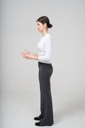 Vue latérale d'une femme en pantalon noir et chemise blanche faisant des gestes