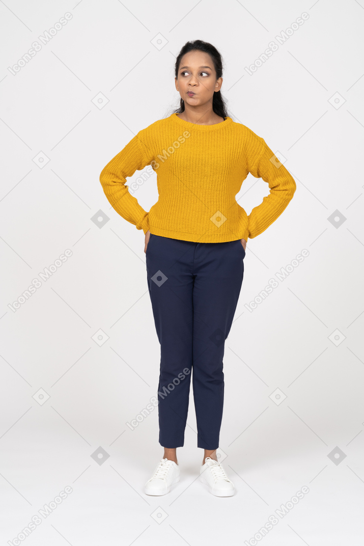 Front view of a girl in casual clothes posing with hand on hips and making faces