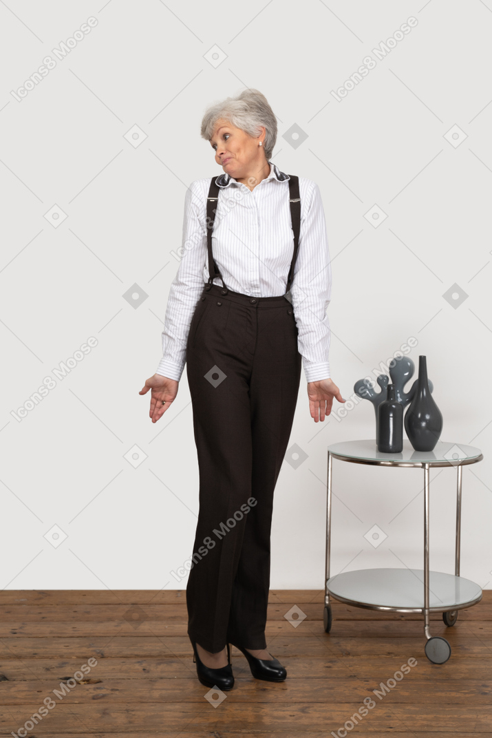 Front view of a shy old lady in office clothing outspreading hands
