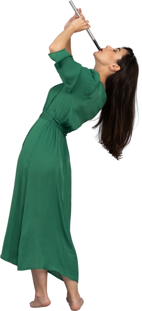 Vista lateral de uma jovem de vestido verde tocando flauta enquanto se inclina para trás