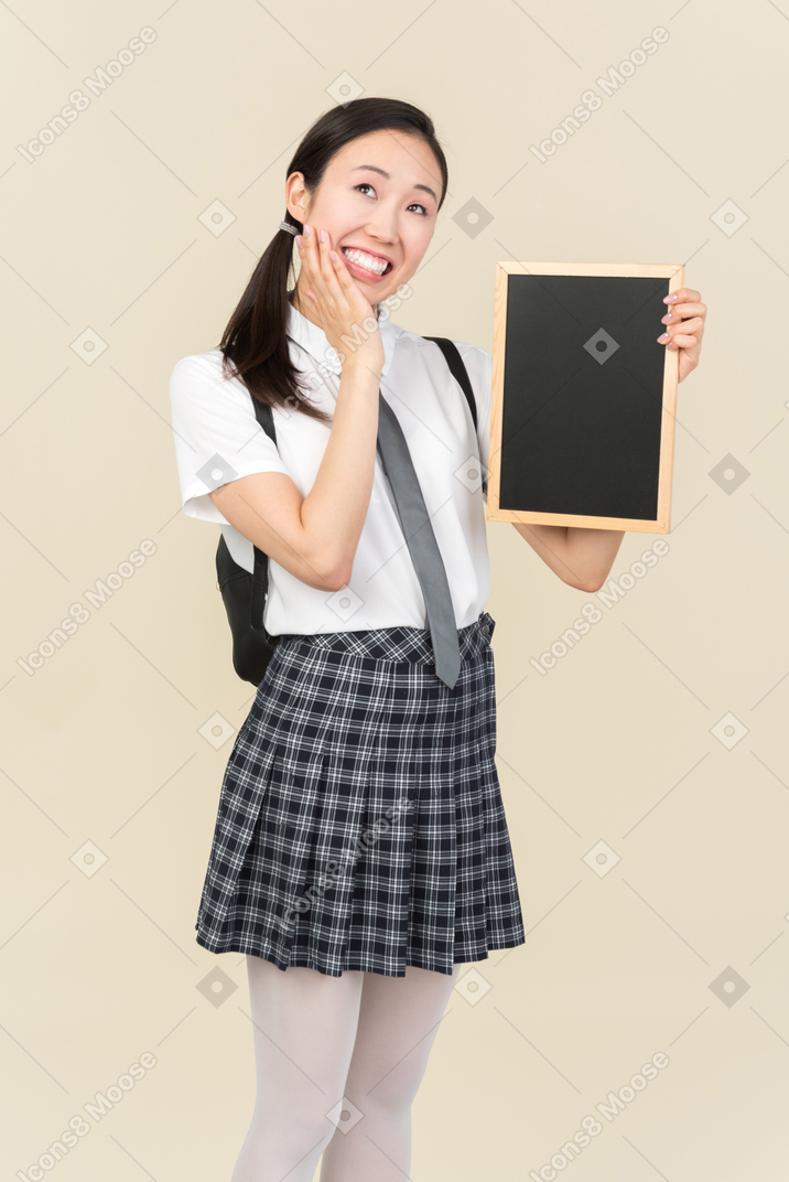 Dreamy asian school girl holding small blackboard