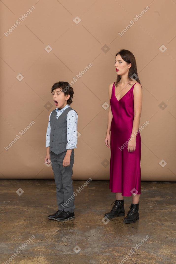 Сонная женщина в красном платье и мальчик в сером жилете костюма