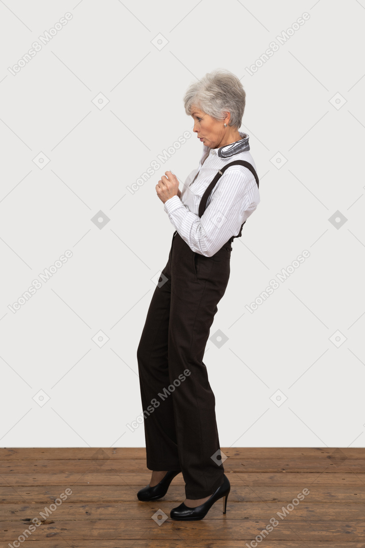 Side view of a scared old lady raising her hands