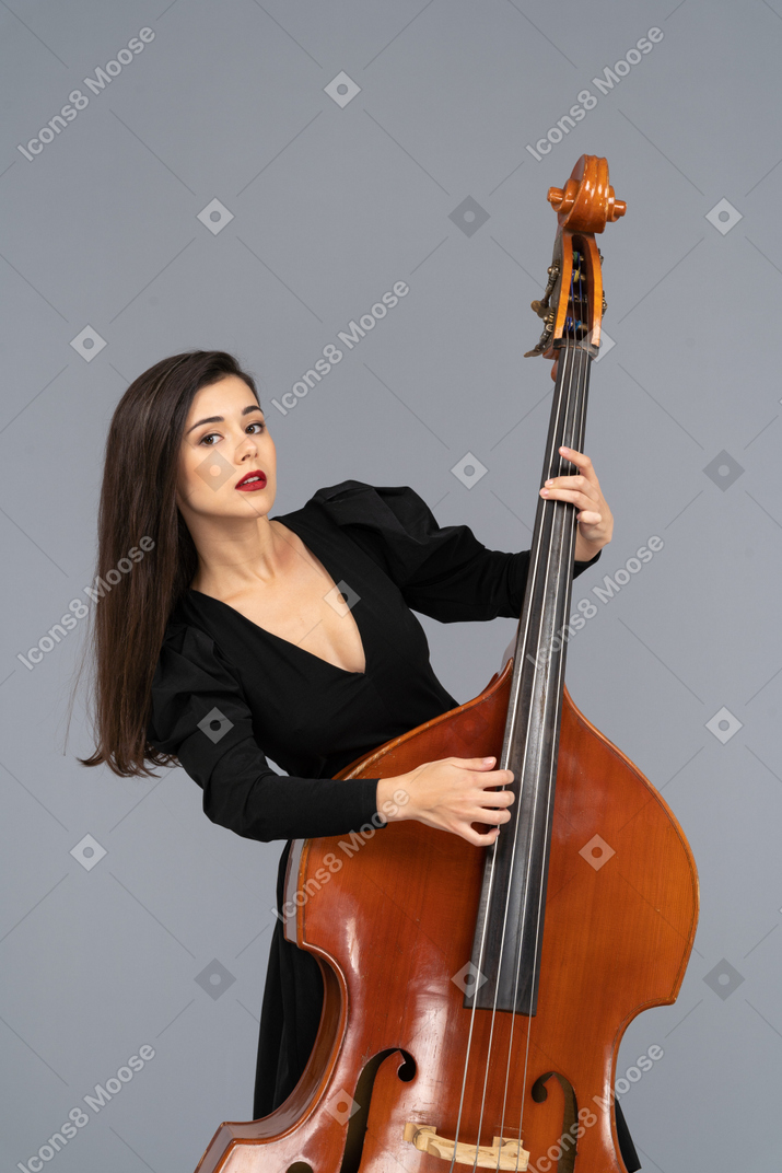 彼女のコントラバスを演奏する黒いドレスを着た若い女性のクローズアップ