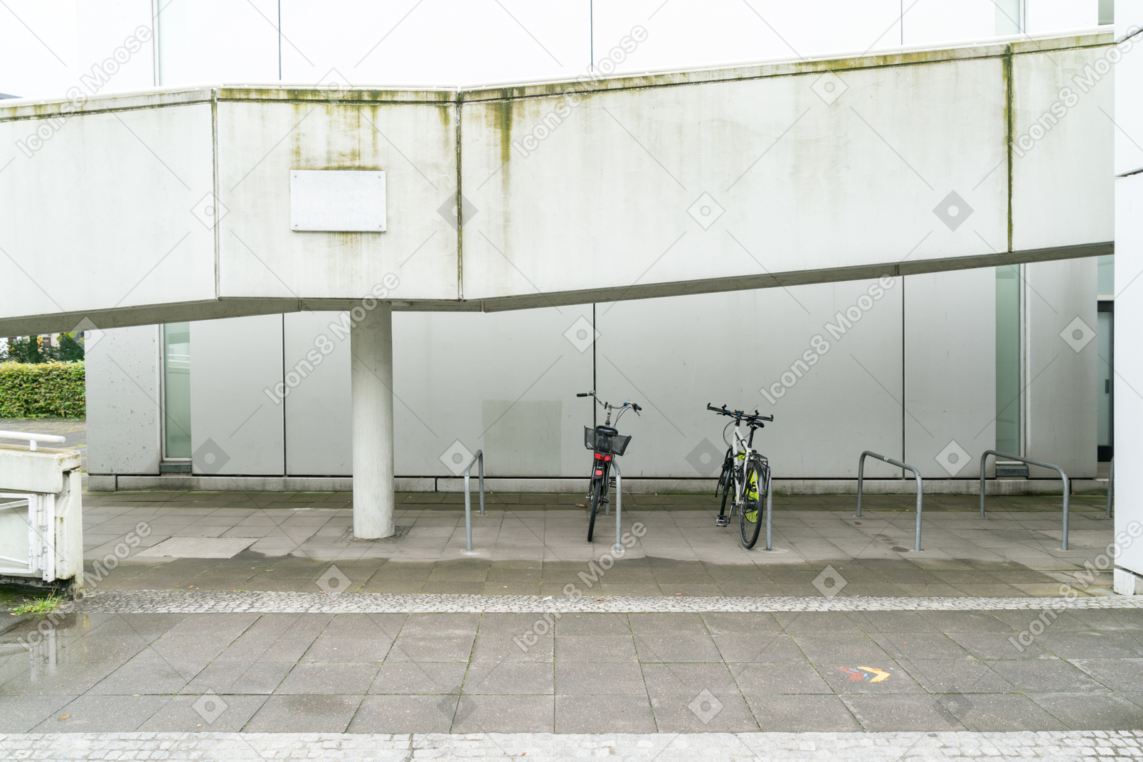 Duas bicicletas no estacionamento em frente ao prédio branco
