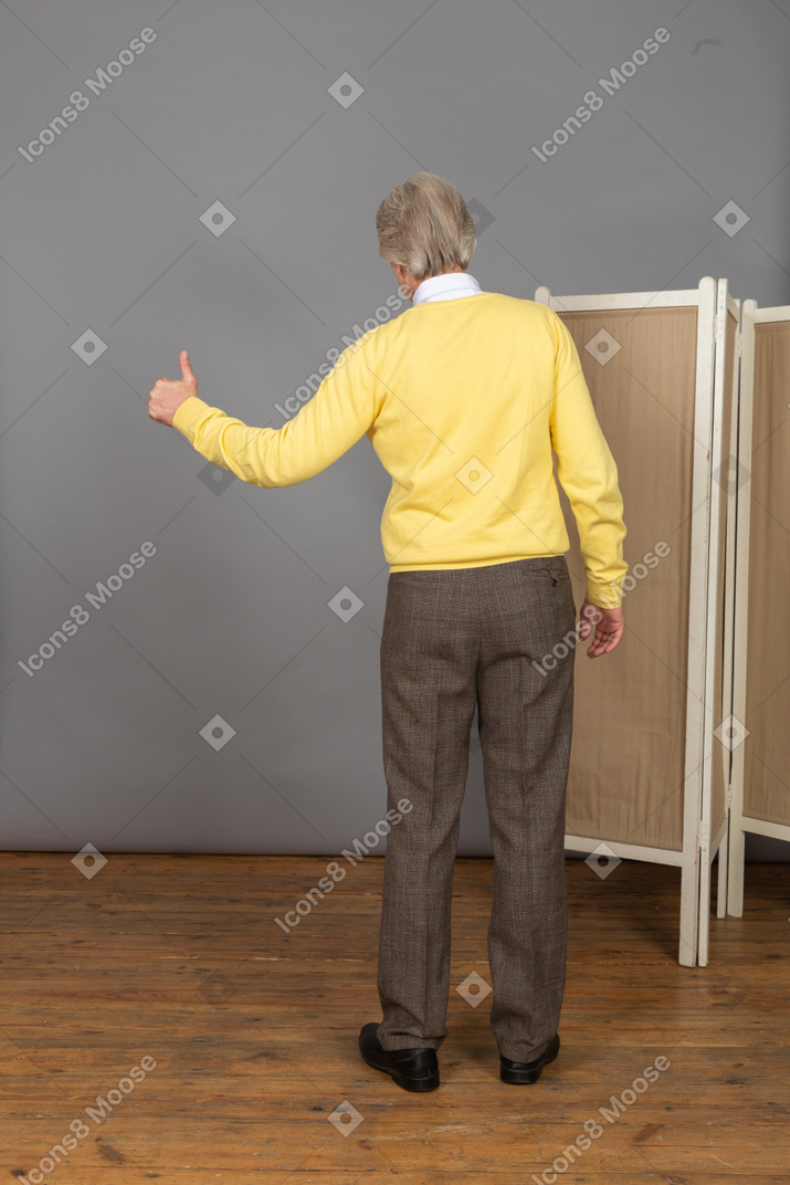 Back view of an old man showing a thumb up