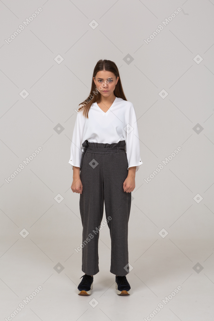 Front view of an angry young lady in office clothing looking at camera and clenching fists