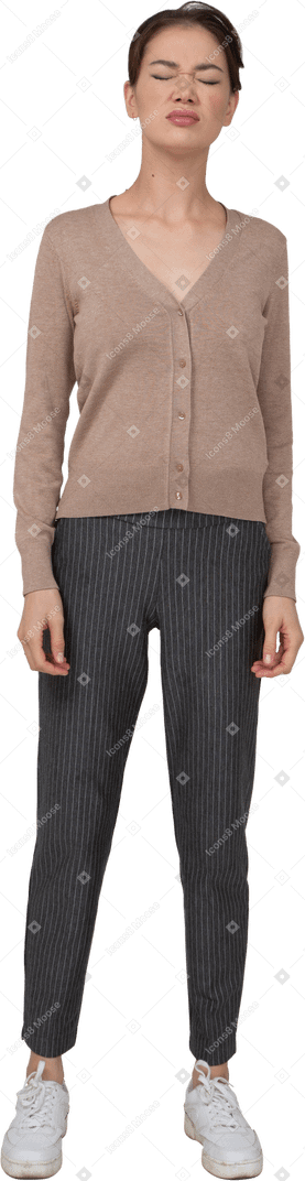 Vue de face d'une jeune femme en pull et pantalon debout avec les yeux fermés