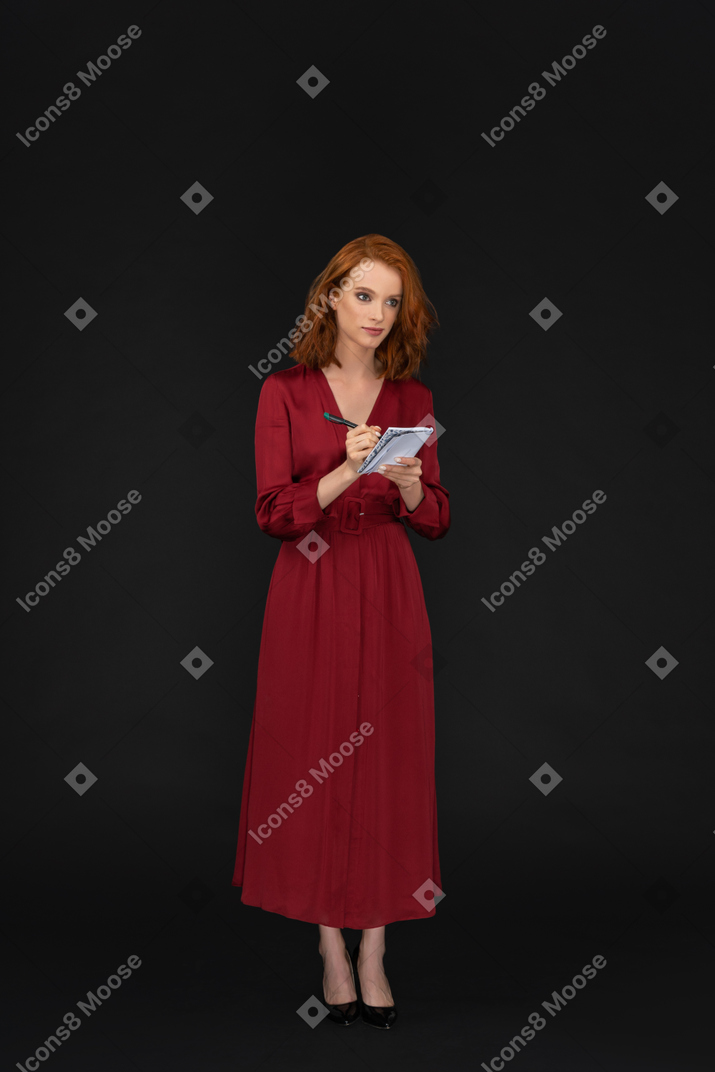 Beautiful sexy woman dressed in red and writing in a notepad