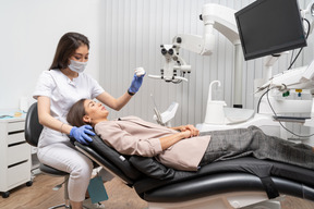 A figura intera di un dentista femmina e la sua paziente guardando il modello di denti