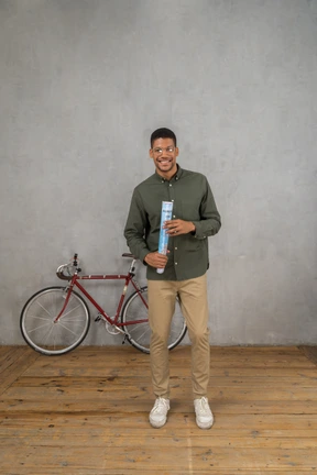 Front view of a man smiling and holding a rolled-up map