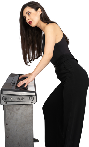 Side view of a serious young lady in black suit playing the piano