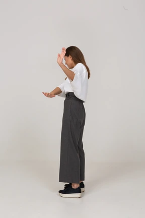 Vista lateral de una señorita reacia en ropa de oficina extendiendo el brazo