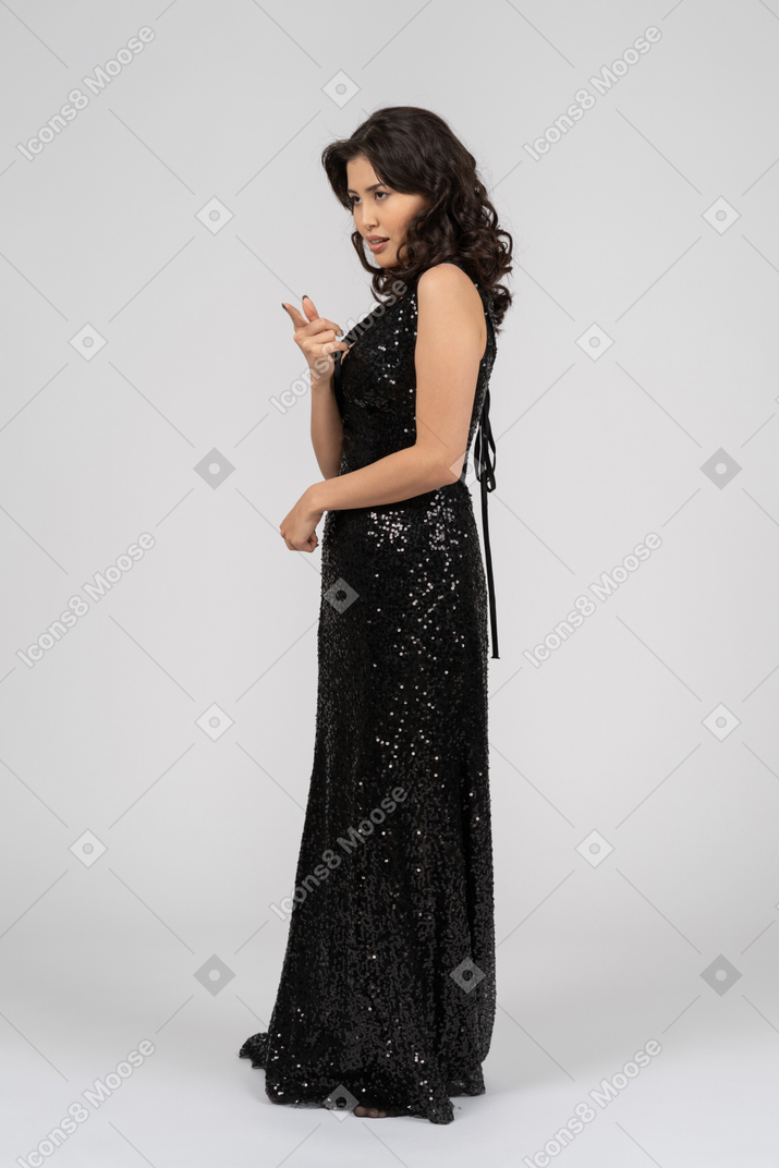 Frau im schwarzen abendkleid zeigt auf etwas