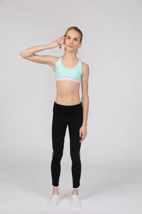 Front view of a teen girl in sportswear touching head