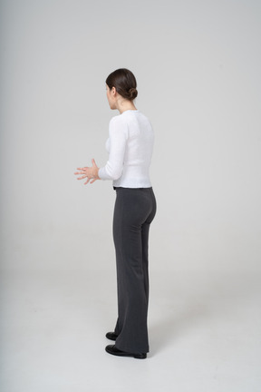 Vista laterale di una donna in pantaloni neri e camicetta bianca che gesticola