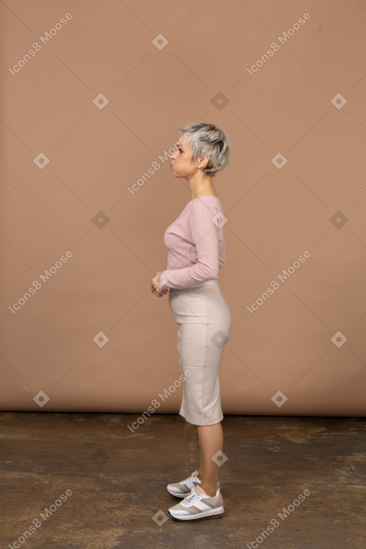 Vista lateral de uma mulher em roupas casuais com as bochechas bufantes