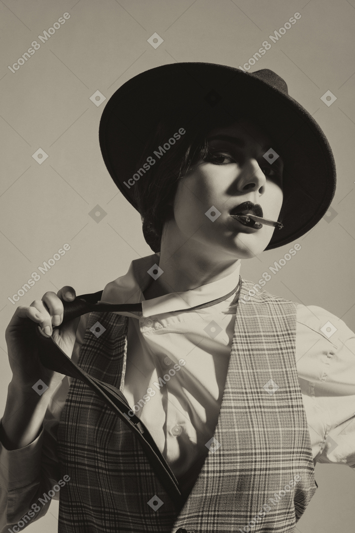 Elegant woman in a hat removing a tie