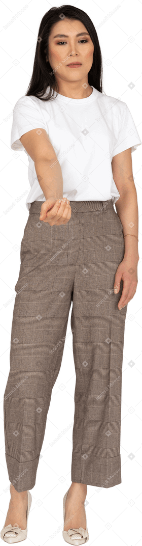 Vista frontal de una joven en pantalones y camiseta extendiendo su mano