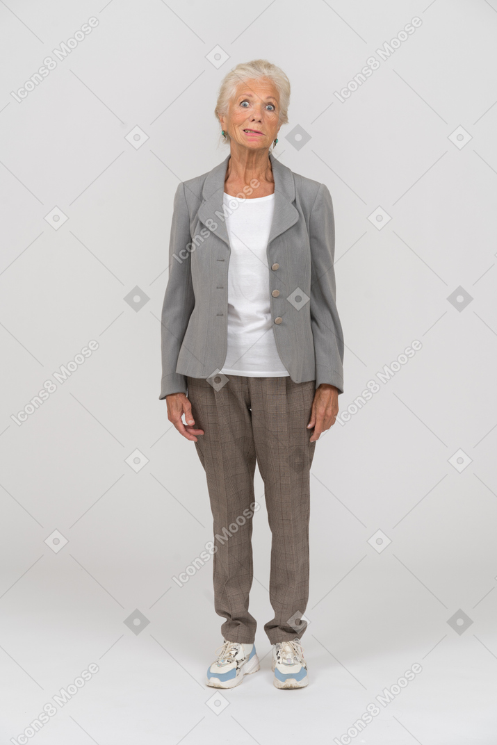 Vorderansicht einer alten dame im anzug, die grimassen macht