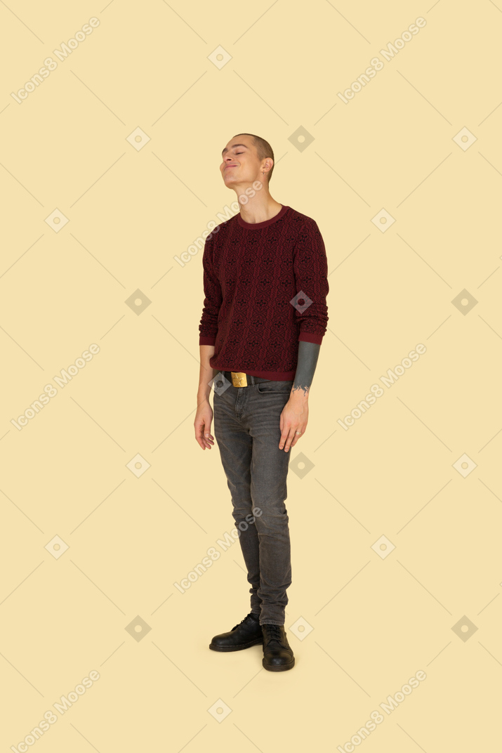 Трехчетвертный вид на забавного гримасничающего молодого человека в свитере для чтения