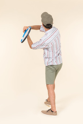 Young caucasian man holding tennis racket and standing back to camera