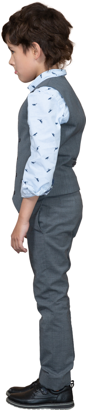 Vista lateral de un niño con traje gris parado