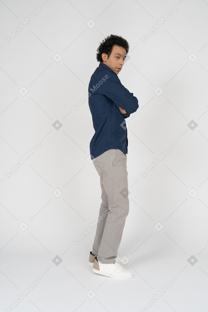Side view of a man in casual clothes posing with crossed arms