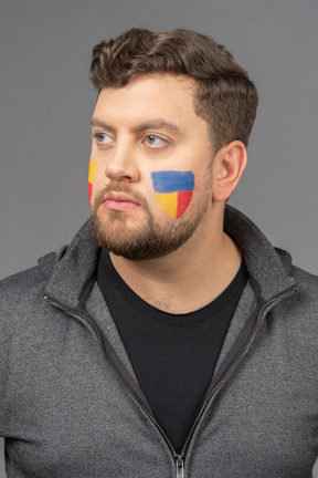 Front view of a male football fan with colorful face art