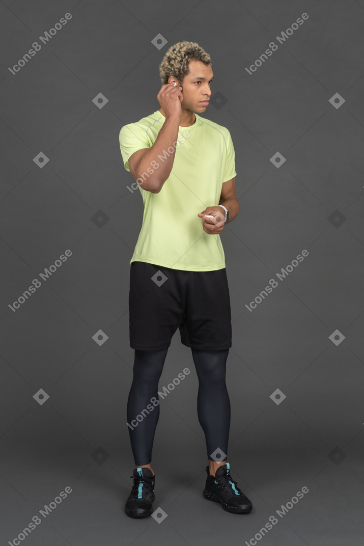 Homem com roupas de ginástica colocando fones de ouvido