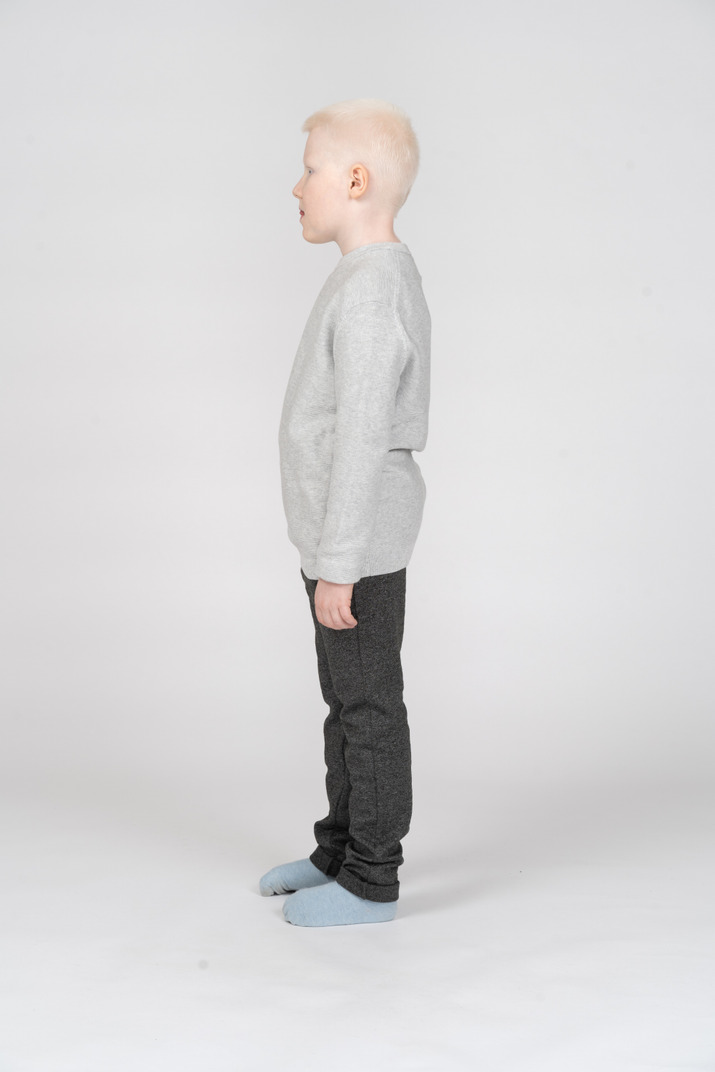 Side view of a kid boy in casual clothes looking aside and showing tongue