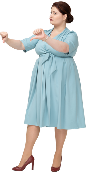 Vista frontal de una mujer con vestido azul mostrando los pulgares hacia abajo