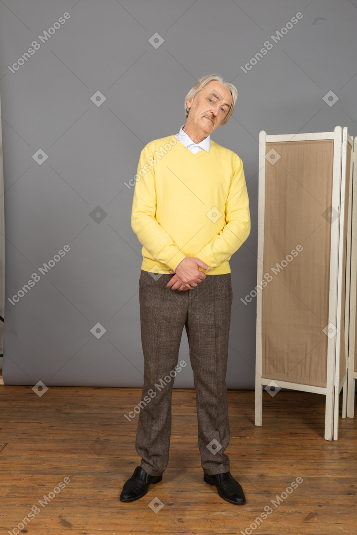 Front view of an old man holding hands together while standing still