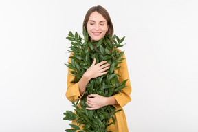 Young woman hugging green branches