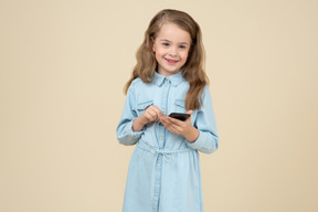 Милая маленькая девочка держит смартфон