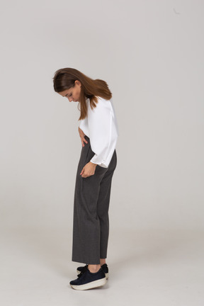 Vista laterale di una giovane donna in abiti da ufficio che si aggiusta i pantaloni