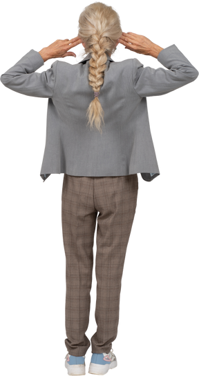 Rear view of an old lady in suit standing with hands behind head