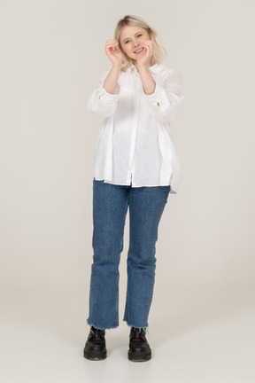 Vista frontal de una mujer rubia en ropa casual mostrando un gesto de corazón y haciendo muecas