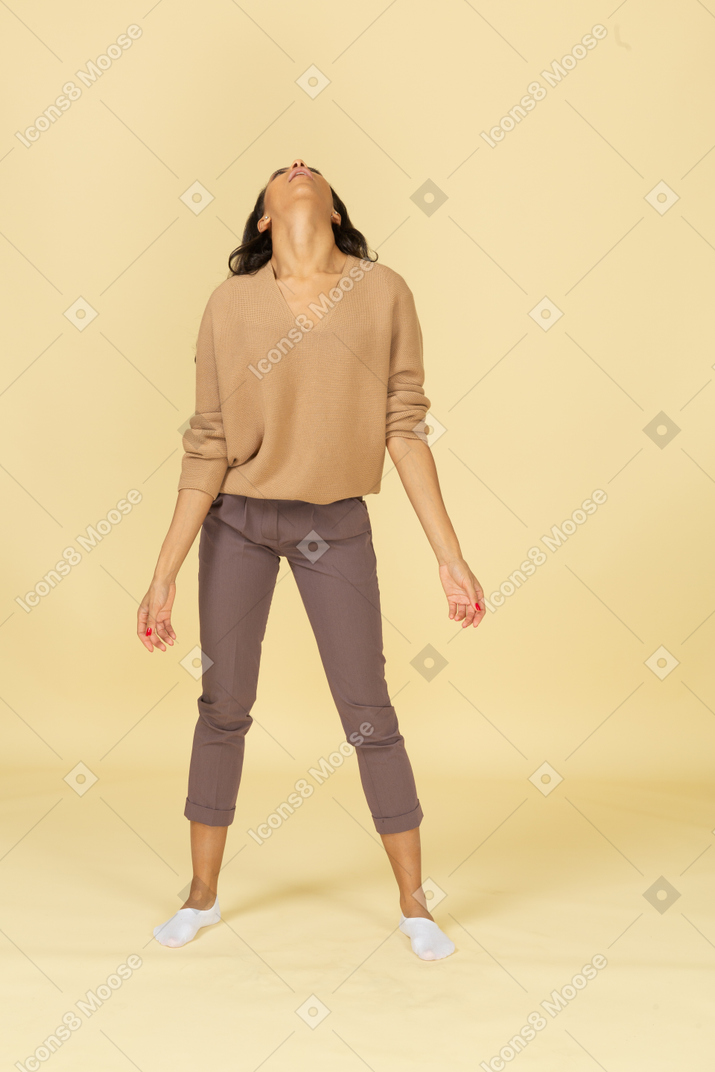 Vista frontal de una joven de piel oscura de pie con los brazos extendidos