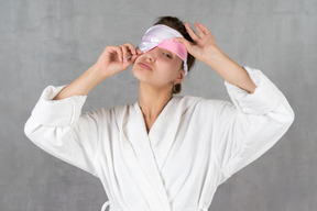 Woman in bathrobe with sleep mask covering one eye