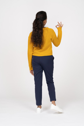 Rear view of a girl in casual clothes showing ok sign