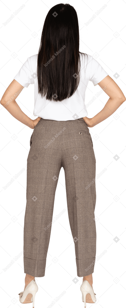 Vista posteriore di una giovane donna in calzoni che mette le mani sui fianchi