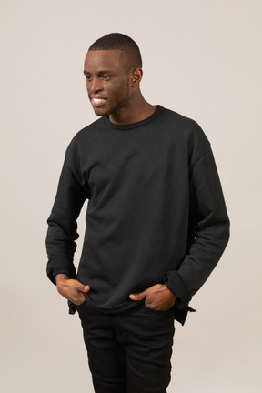 Jeune homme en vêtements noirs souriant et regardant de côté