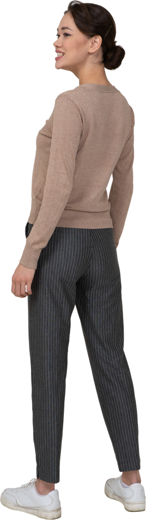 Vista posteriore di tre quarti di una donna sorridente in pullover e pantaloni