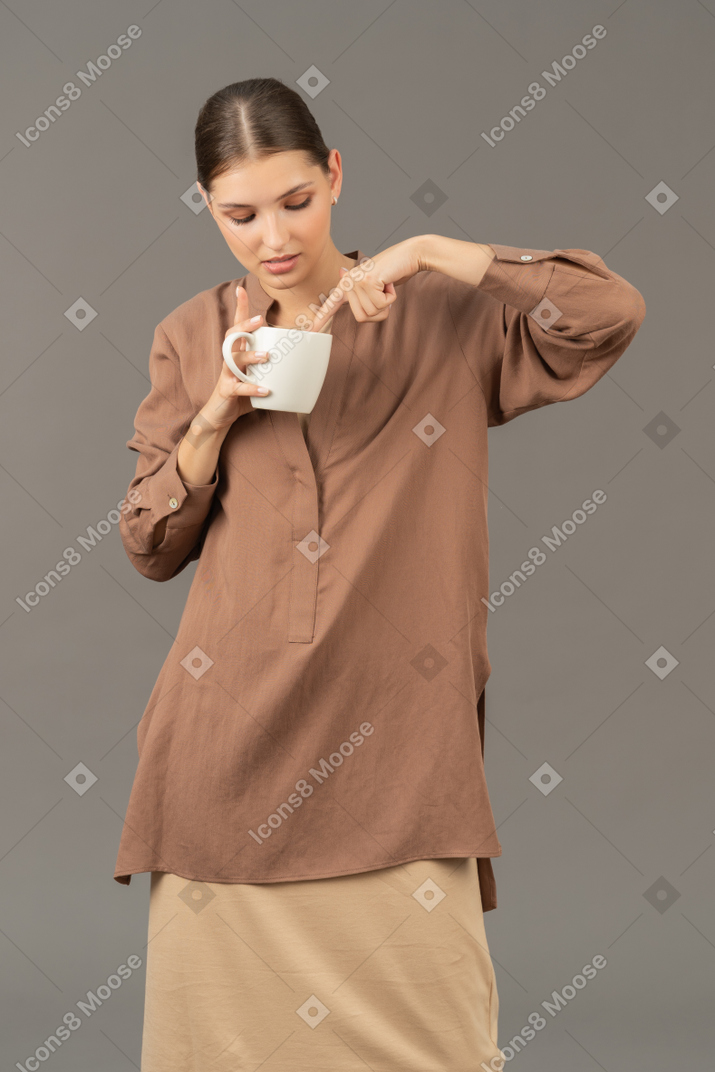 커피 컵에 손가락을 담그고 있는 젊은 여성