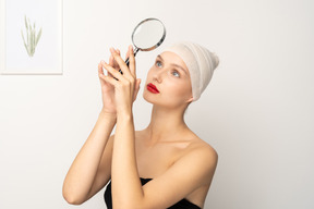 Portrait of a young woman holding up magnifying glass